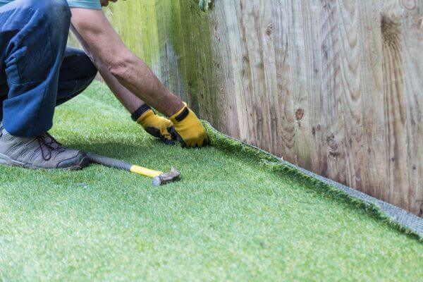 The Pros And Cons Of Artificial Grass A man installing artificial lawn